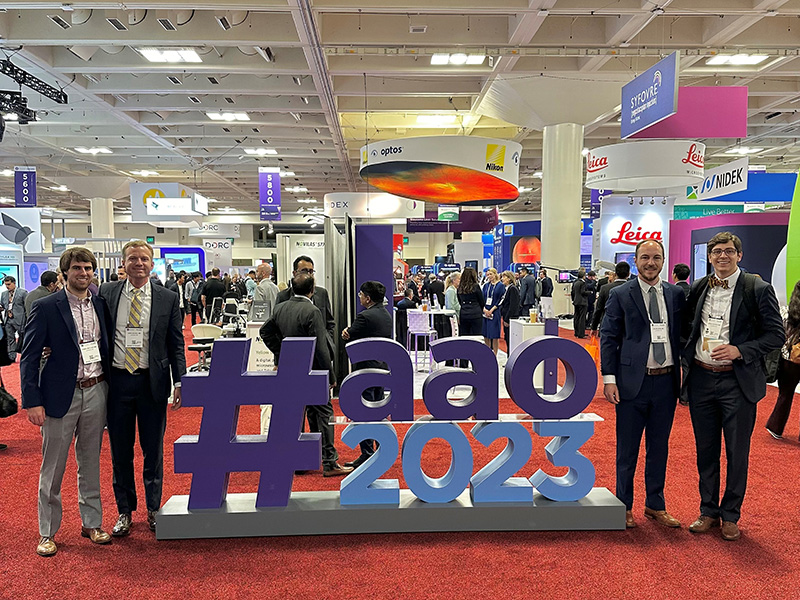 Five people pose beside a large "#aao 2023" sign at a professional event.